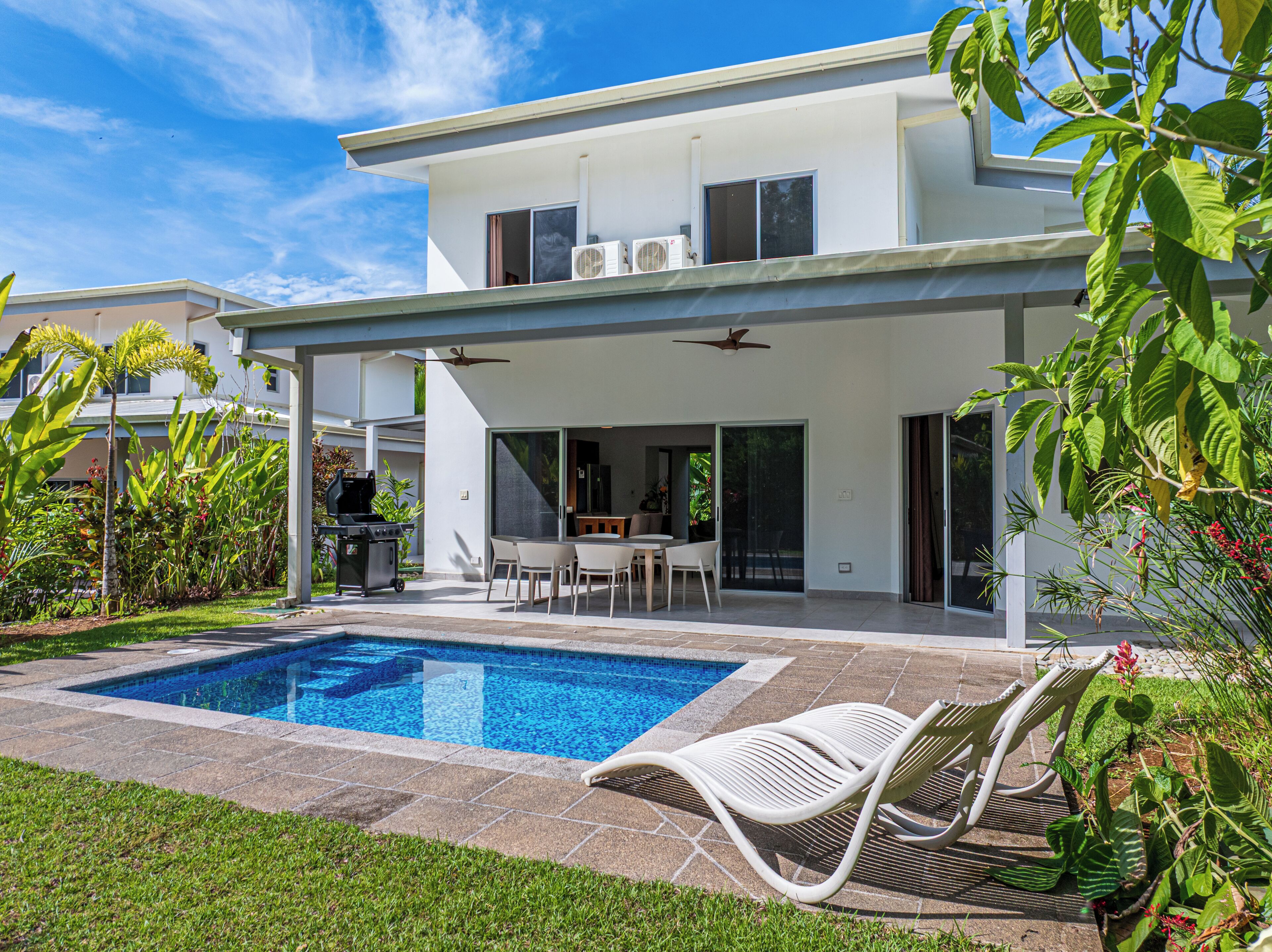 Uma casa moderna de dois andares com piscina, área de estar externa e varanda coberta.