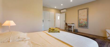 Habitación de hotel con cama, escritorio, silla, aire acondicionado y un cuadro en la pared.