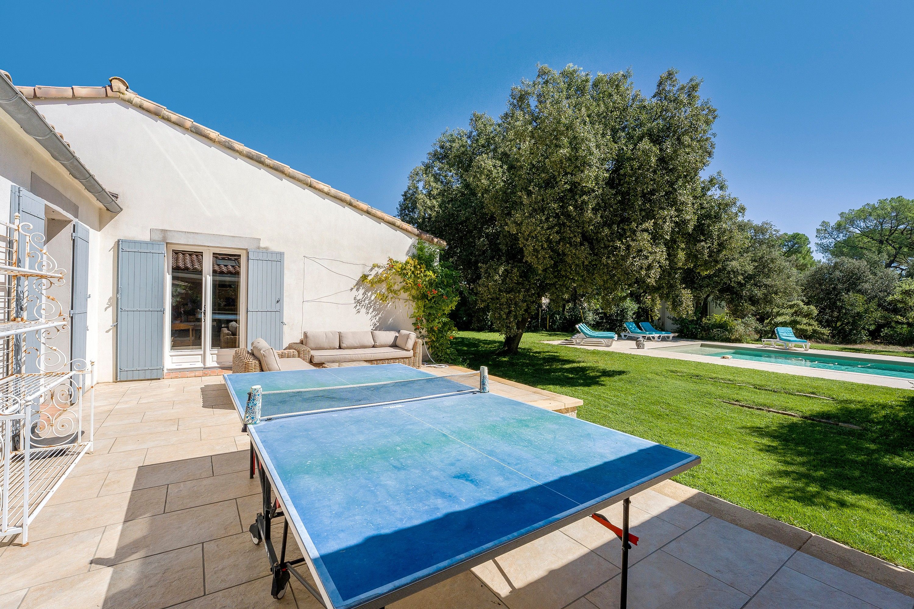 A residential property with a tennis court, outdoor seating, and a swimming pool.