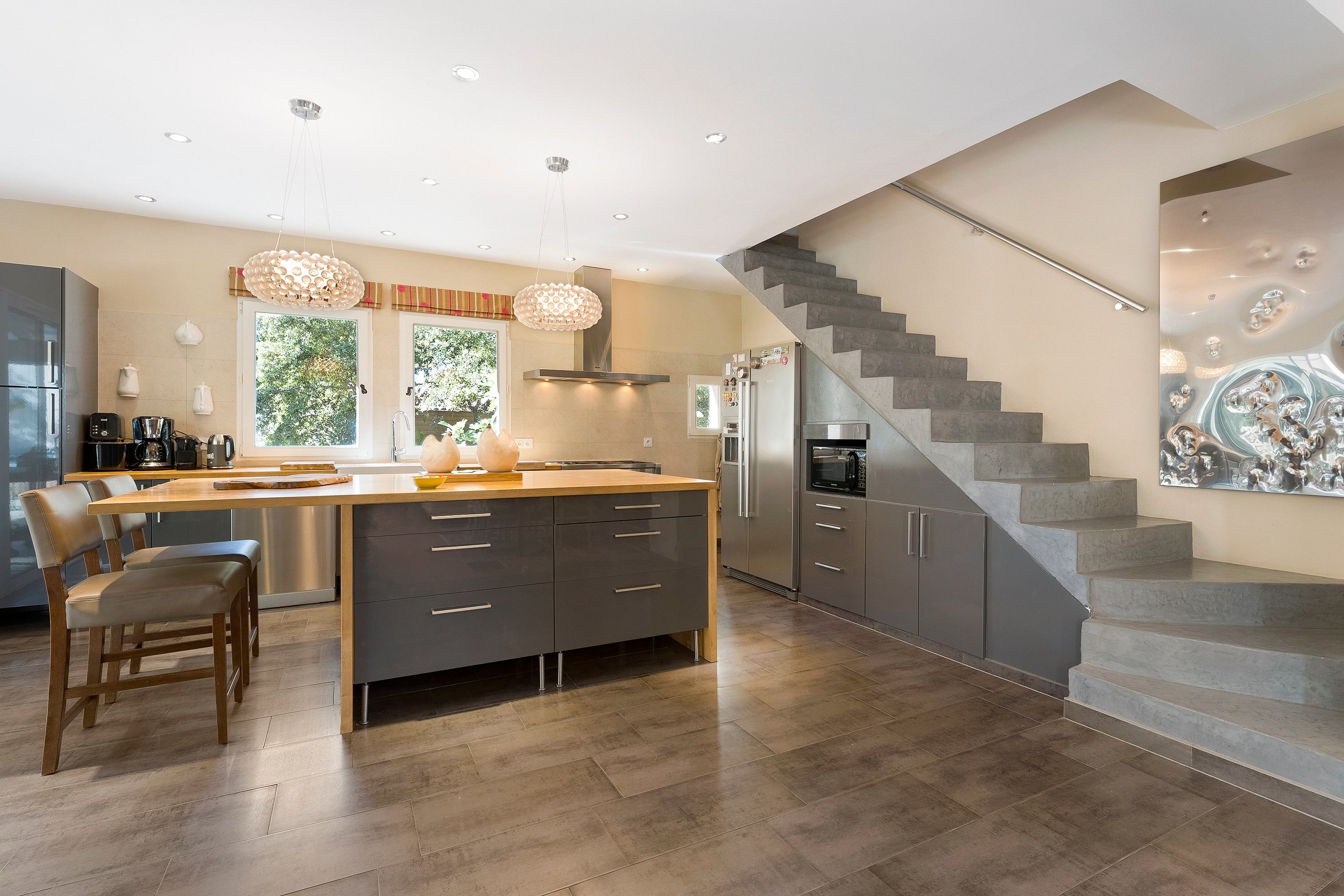 A modern kitchen with a central island, stainless steel appliances, and a staircase leading to an upper level.