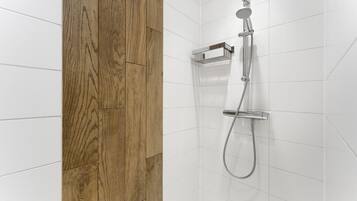 Eine Dusche mit Handbrause und Bedienfeld an der Wand.