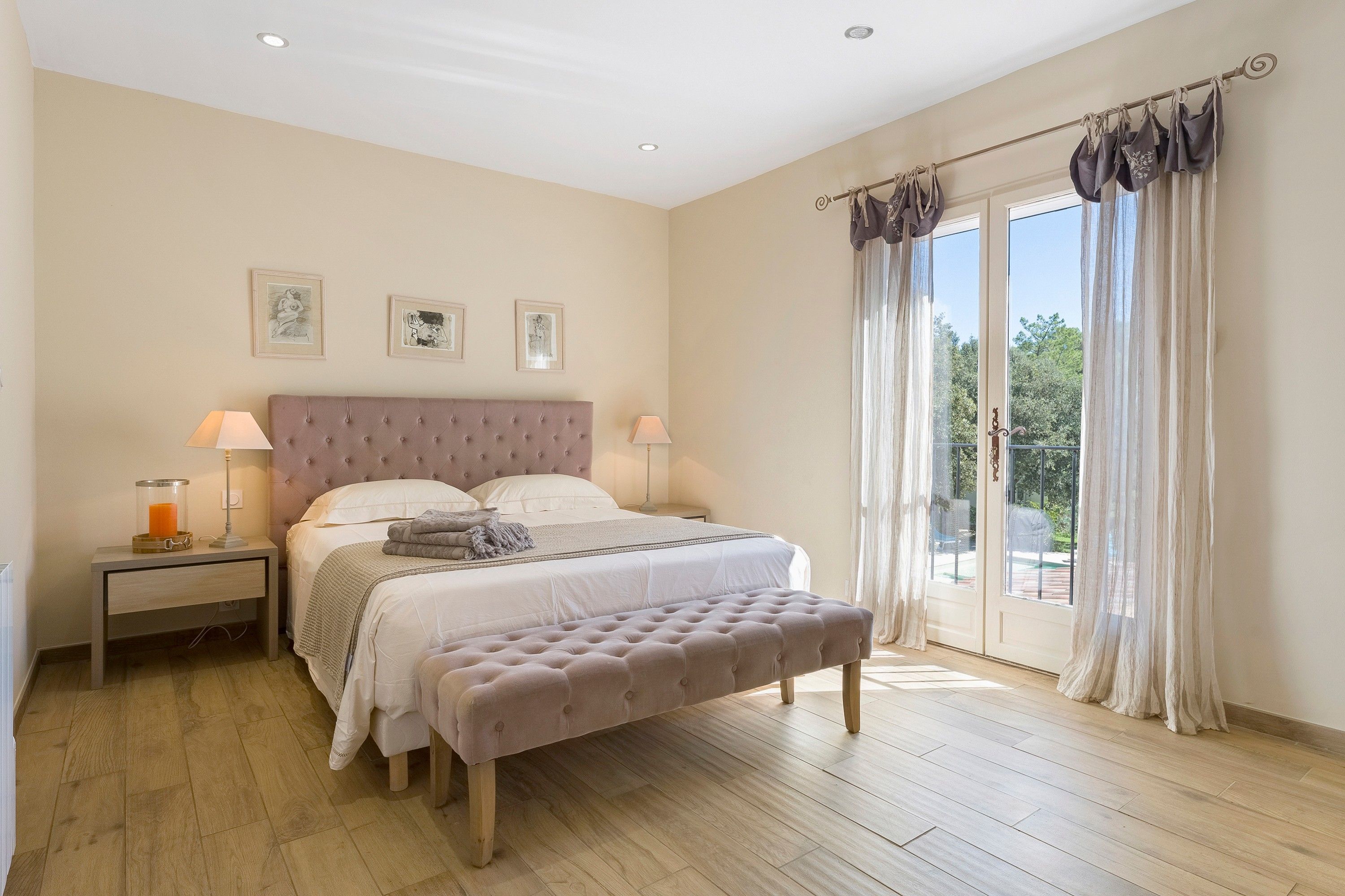 Une chambre avec un grand lit, une table de chevet, un banc et une vue sur l’extérieur grâce à une porte vitrée.
