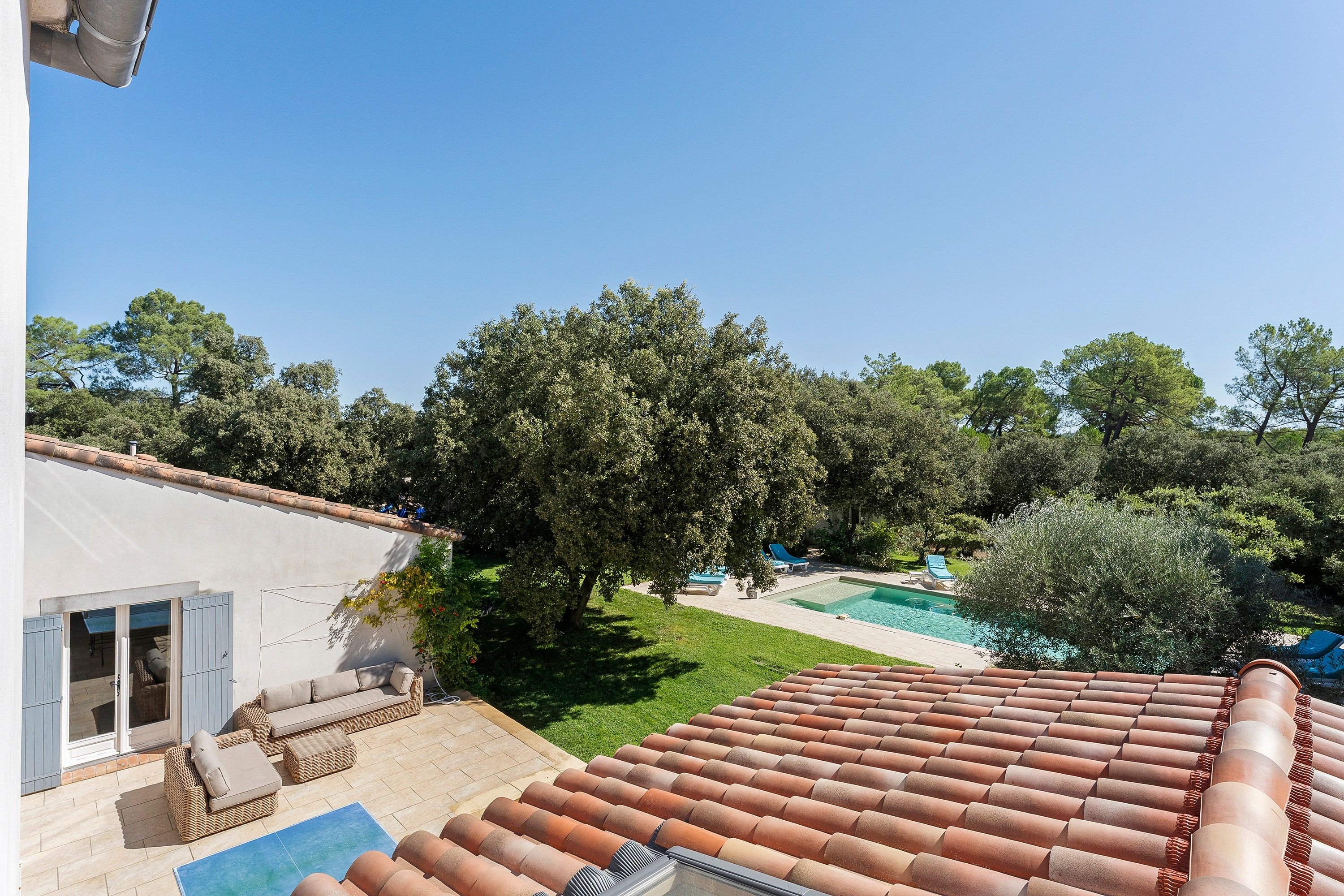 A residential property with a swimming pool, outdoor seating, and a garden.