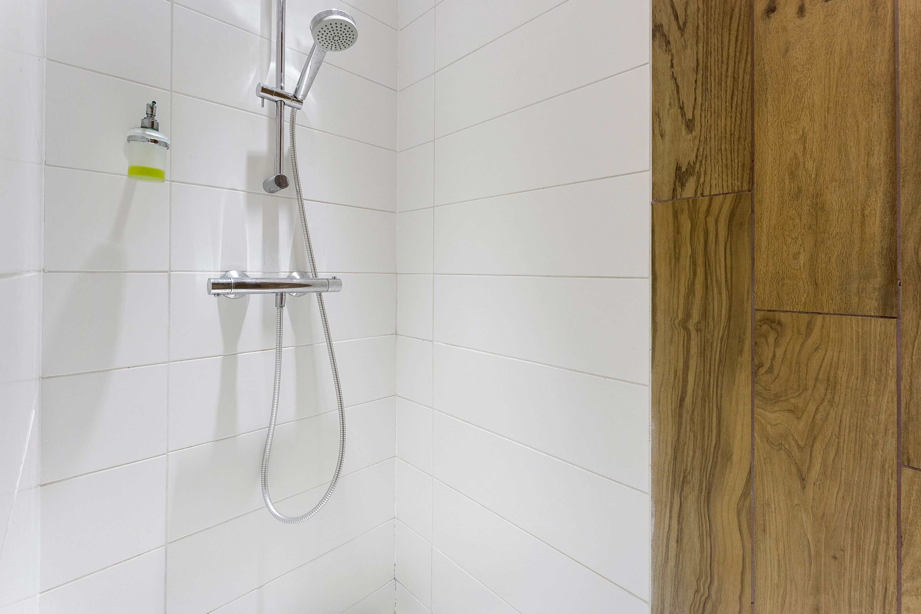 Eine Dusche mit Handbrause und Armaturen an der Wand.