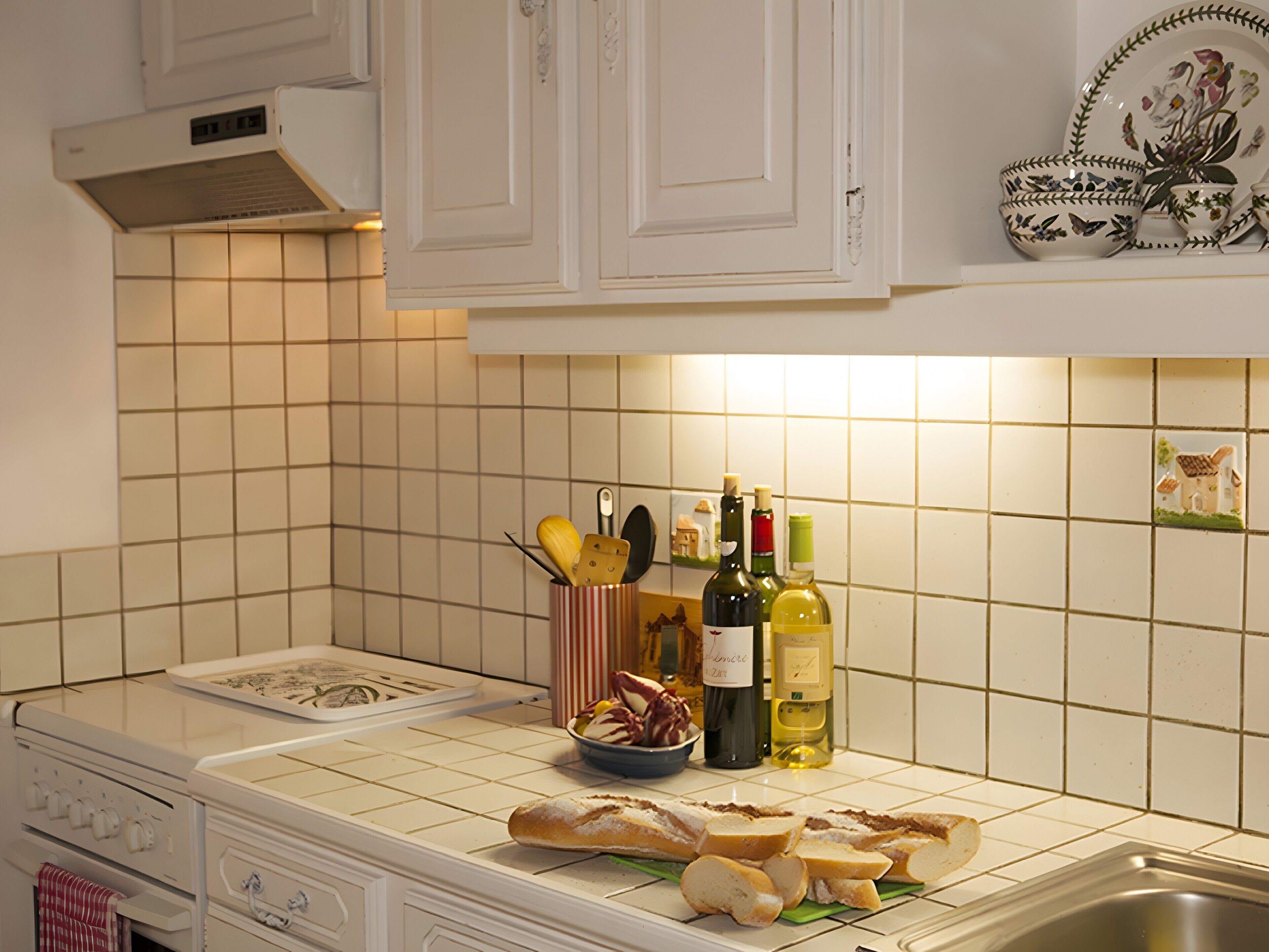 A kitchen with white cabinets, a tiled backsplash, a stove, and a sink.