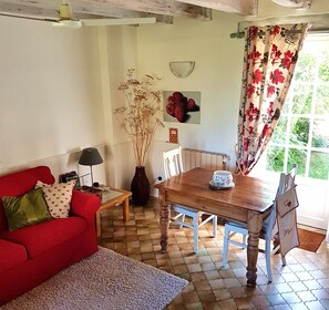 Ein gemütliches Wohnzimmer mit einem roten Sofa, einem Holzesstisch und einer Vase mit Trockenpflanzen.