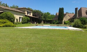 Ein Wohnhaus mit Swimmingpool, überdachter Terrasse und gepflegtem Rasen.