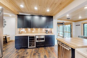 Une cuisine moderne avec des meubles de couleur sombre, un plan de travail en bois et des appareils électroménagers intégrés.