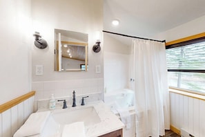 Un baño con lavamanos, espejo, inodoro y cortina de ducha.