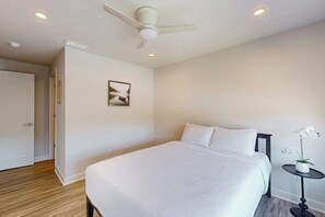 A hotel room with a bed, a ceiling fan, recessed lighting, a small table with a plant, and a door leading to another room. - 3 BR townhouse with balcony - fireplace - near beach (Lake George)