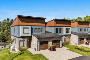 A row of modern, two-story houses with attached garages, featuring a mix of siding and stonework, set in a suburban neighborhood. - 3 BR townhouse with balcony - fireplace - near beach (Lake George)