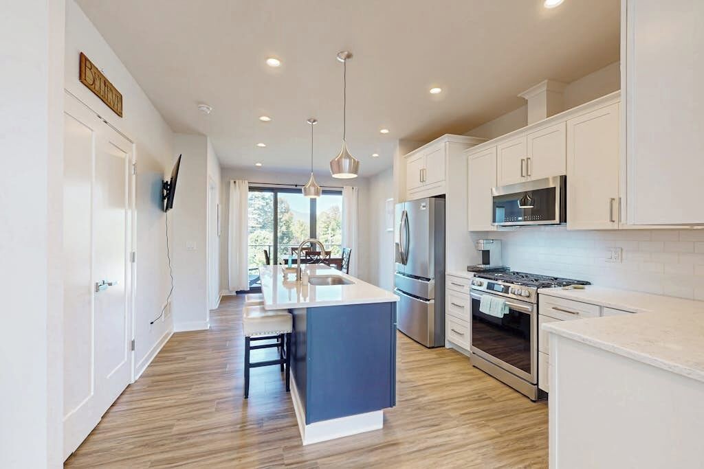 A modern kitchen with a central island, stainless steel appliances, and a view to the outdoors.