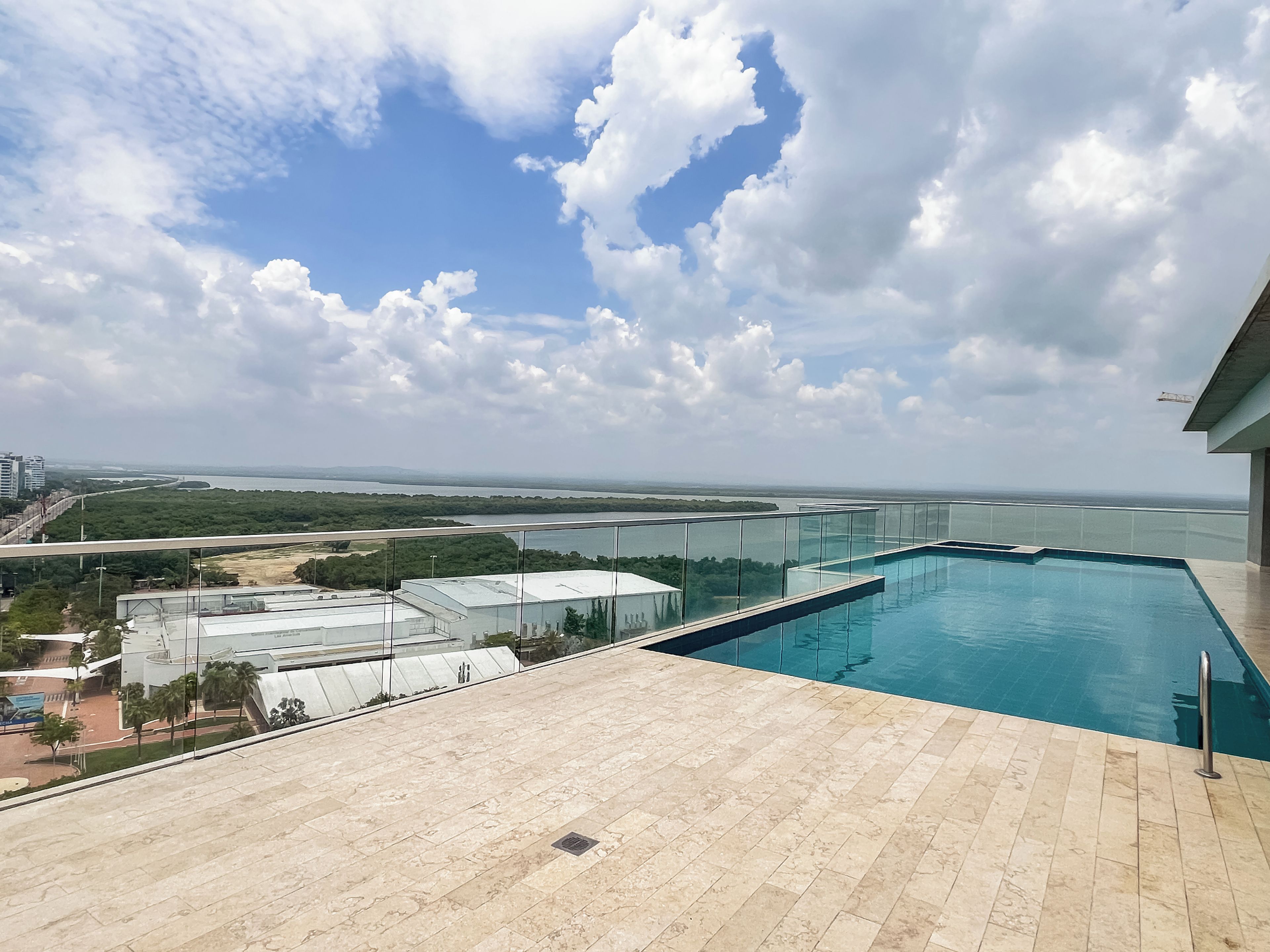 Une piscine sur le toit offrant une vue dégagée sur une rivière et le paysage urbain lointain.