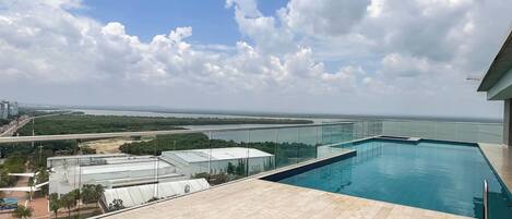 A rooftop pool with a clear view of a river and distant cityscape.