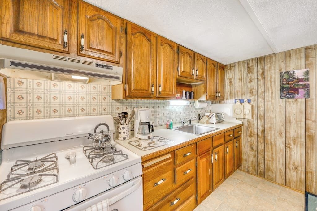 A kitchen with wooden cabinets, a white stove, and a tiled backsplash.