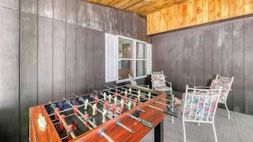 Une pièce avec une table de baby-foot, deux chaises et une fenêtre.