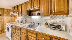 Una cucina con mobili in legno, un fornello, un lavello e un tostapane.