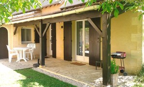 A patio area with a table and chairs, a covered seating area, and a door leading to a covered entrance. - Holiday Home 'Grace's Gate At Domaine De Leygue' with Wi-Fi (Bourniquel)