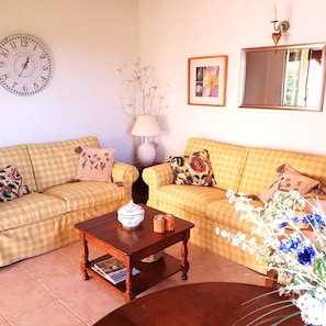 A living room with two checkered sofas, a wooden coffee table, a clock, a lamp, a framed picture, and a mirror. - Holiday Home 'Grace's Gate At Domaine De Leygue' with Wi-Fi (Bourniquel)