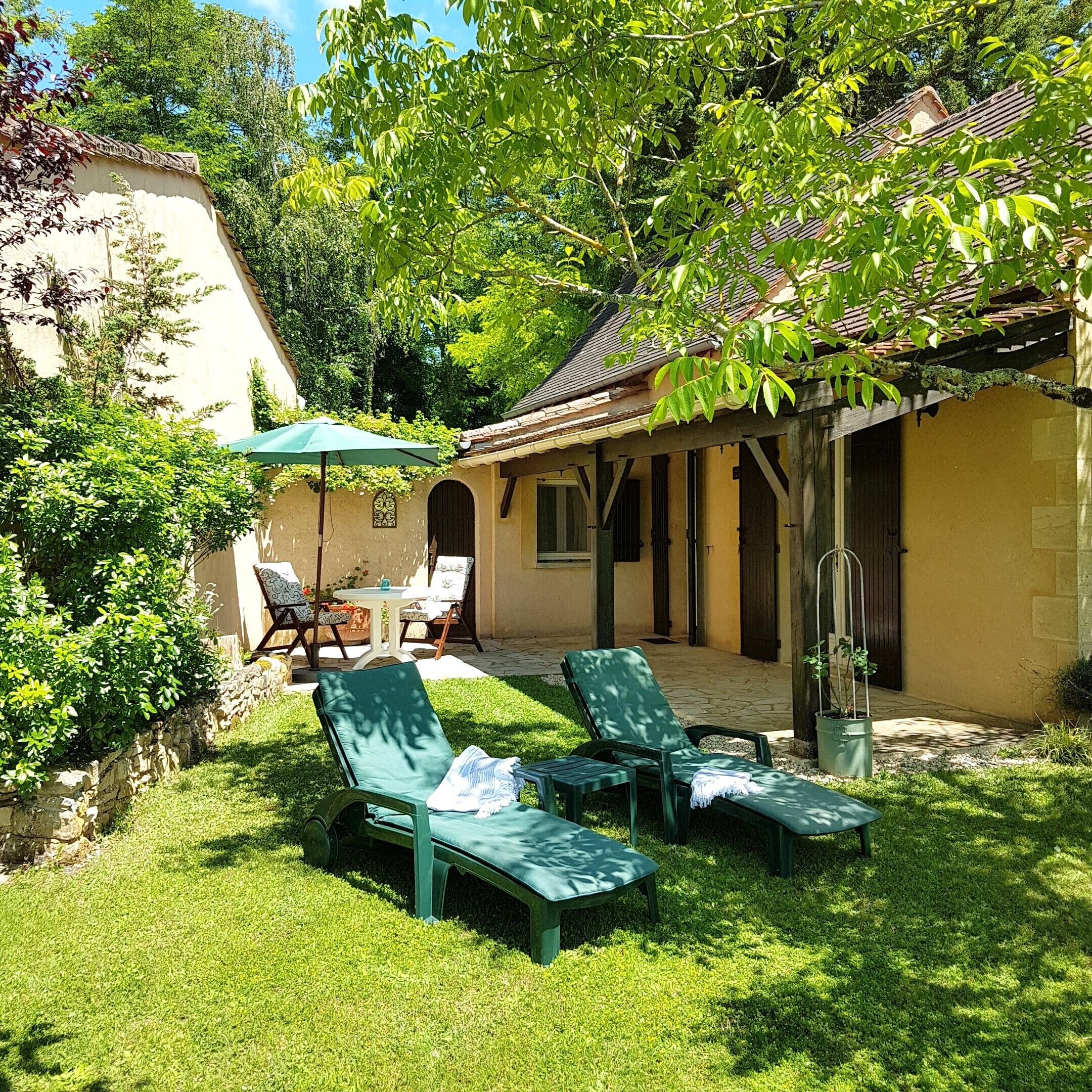 Un espace patio comprenant deux chaises longues, une table avec des chaises et un coin salon abrité.