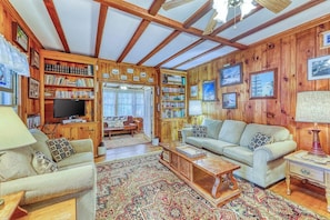 Ein gemütliches Wohnzimmer mit Holzwänden, einem Kamin, einem Fernseher und einem Bücherregal.