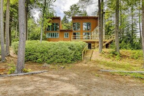 A cabin with a wooden exterior, a deck, and a staircase leading to the entrance. - Unique 4BR Lakefront Adirondacks - Dock (Chestertown)