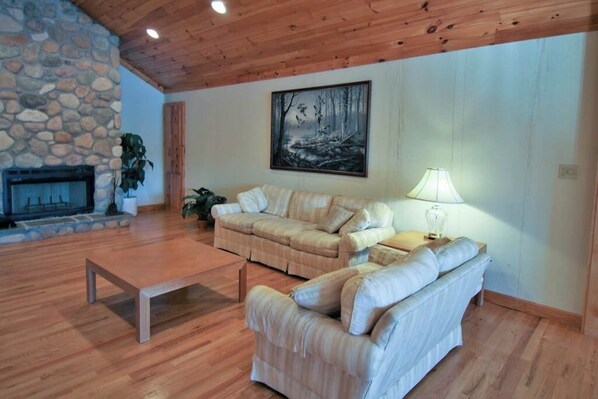 A living room with a stone fireplace, a painting, a sofa, a coffee table, and a lamp.