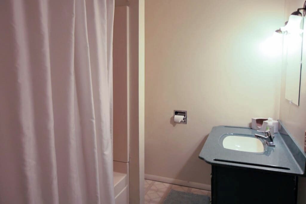 Une salle de bain équipée d’un lavabo, d’un miroir et d’un distributeur de papier toilette.