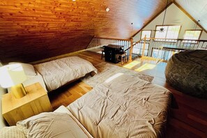 Une chambre avec un plafond de style industriel, un lit, une table de chevet et un escalier menant à un niveau supérieur.