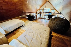 A loft bedroom with two beds, a large bean bag, and a desk with a chair. - 1BR vineyard stay with firepit, grill, & EVC (Keuka Park)