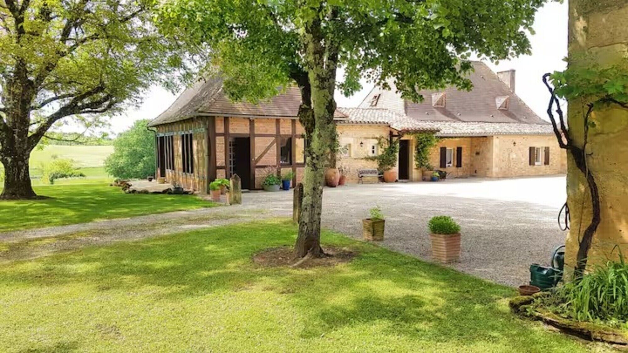 En traditionell byggnad i sten med en stor, öppen innergård, omgiven av välskött gräsmatta och träd.