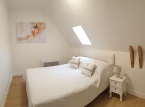 A bedroom with a bed, bedside table, lamp, and a painting on the wall. - Holiday Home 'Barn Cottage' with Wi-Fi (Bourniquel)