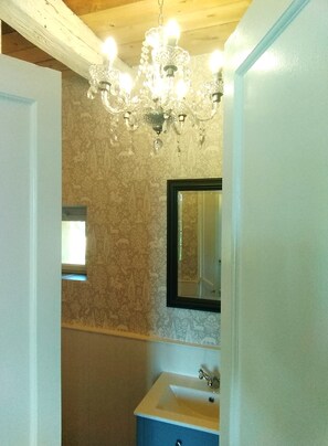 Ein Badezimmer mit einer Chandelier, einem Waschbecken und einem Spiegel.