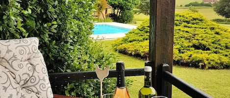 Mesa al aire libre con vistas a una piscina, rodeada de abundante vegetación.