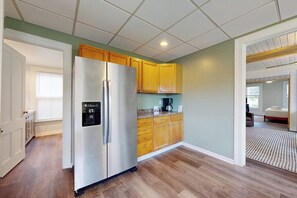 A kitchen with wooden cabinets, a stainless steel refrigerator, and a coffee maker on the countertop. - Walk to Canandaigua Spots, Wine Trail, Lakes (Canandaigua)