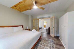 A bedroom with a large bed, wooden ceiling fan, and a view into the kitchen through an open door. - Walk to Canandaigua Spots, Wine Trail, Lakes (Canandaigua)
