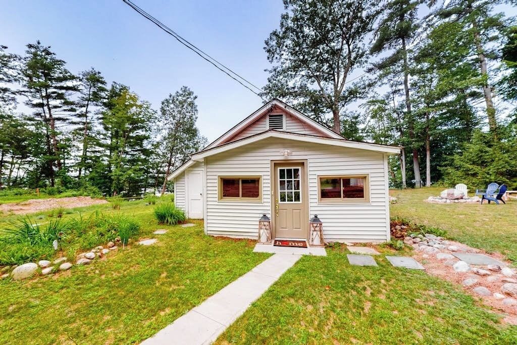A small, single-story house with a front door, two windows, and a small porch area.