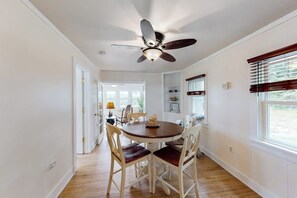 Un coin repas équipé d’un ventilateur de plafond, d’une table ronde et de quatre chaises.