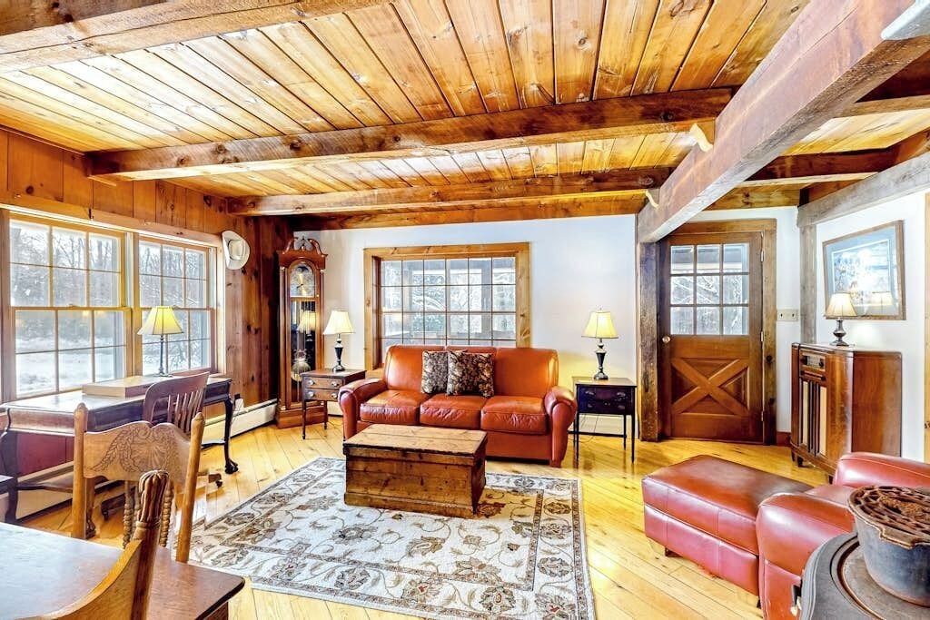 Un salon chaleureux avec un plafond en bois, un canapé en cuir, une table basse en bois et une cheminée.