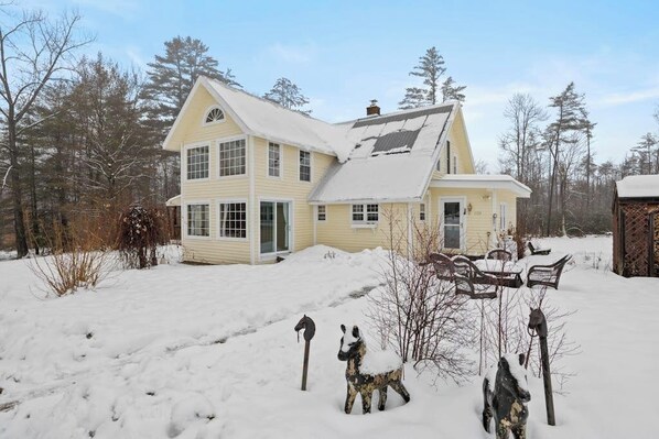 A two-story house with a snow-covered roof and yard.