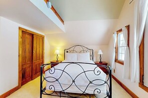 A bedroom with a metal bed frame, wooden wardrobe, and a window with curtains.