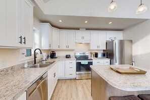 A modern kitchen with white cabinets, stainless steel appliances, and a granite countertop. - 3BR house, dog-friendly, beach access, bbq, withd (Schroon Lake)