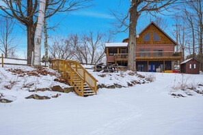 A cabin with a wooden staircase leading to a deck, surrounded by snow-covered ground and trees. - 3BR house, dog-friendly, beach access, bbq, withd (Schroon Lake)