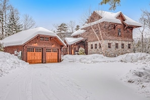 A large wooden cabin with a stone facade, surrounded by snow-covered ground and trees. - Luxe 4BR Mountainview Adirondacks (North Creek)