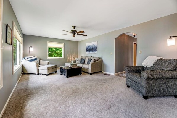 A living room with a ceiling fan, a sofa, a coffee table, and a fireplace. - Keuka Vista|Lakefront 4BR with amazing views, dock & game room (Penn Yan)