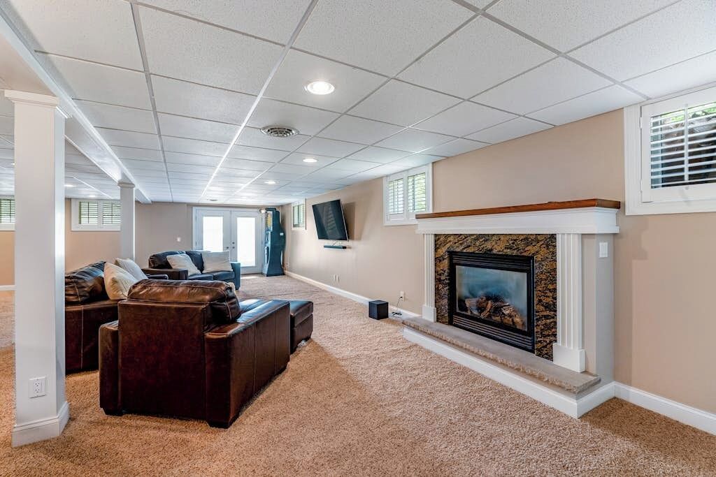 A living room with a fireplace, a large sectional sofa, and a television mounted on the wall.