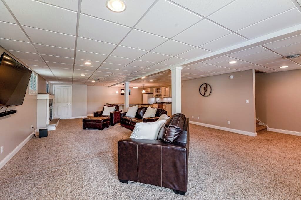 A spacious living room with a large flat-screen TV, a brown leather couch, and a dining area with a table and chairs.