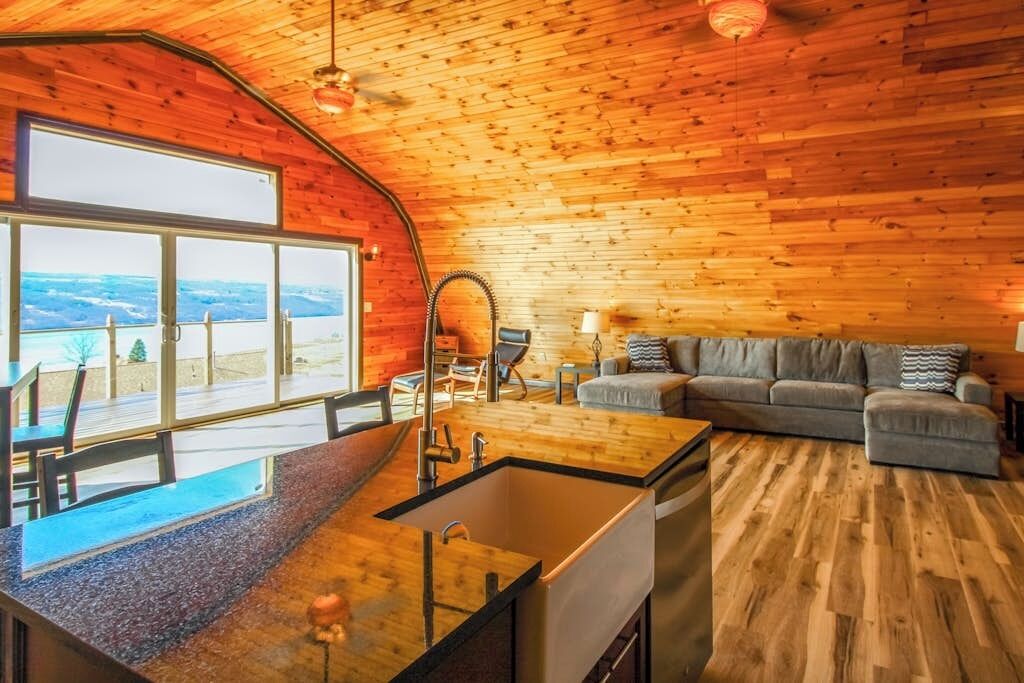 A modern kitchen with a large island, a dining area with a view, and a cozy seating area with a sofa and lamps.