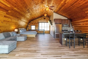 A cozy log cabin interior with a loft bedroom, a dining area, and a kitchen. - Spacious Studio Lakeview Finger Lakes - Balcony (Burdett)