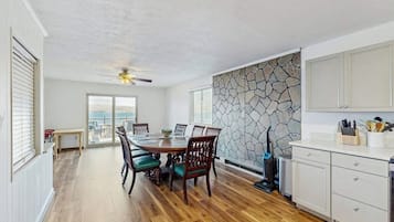 A dining area with a wooden table and chairs, a stone wall, and a view through the window.